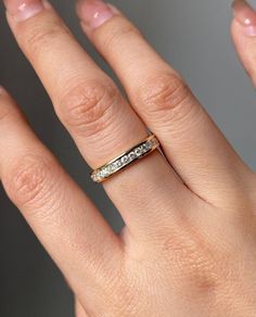 a woman's hand with a wedding ring on top of her finger, and two diamonds in the middle