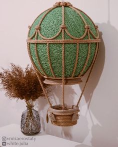 an air balloon is hanging on the wall next to a vase with dry grass in it