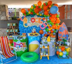 an outdoor birthday party with balloons, decorations and pool floats on the table in front of it