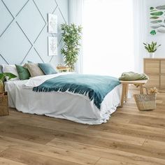 a bed room with a neatly made bed and wooden floors