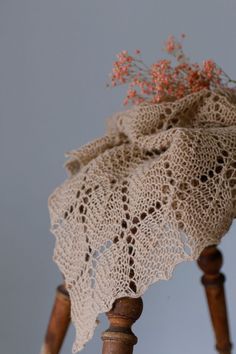 a crocheted doily draped over a wooden chair with flowers on it's back