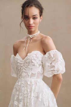 a woman wearing a white dress with flowers on it