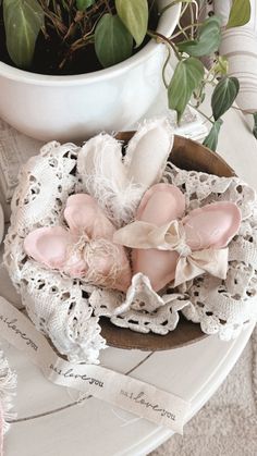 an arrangement of pink eggs in a bowl on a table next to a potted plant