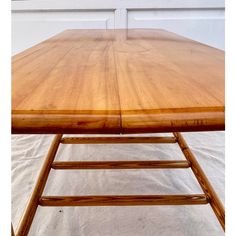 a wooden table sitting on top of a white floor next to a wall and window