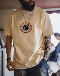 Looking to add some retro flair to your summer wardrobe? Meet the American Retro Guardian Eye Embroidered Cotton Men's T-Shirt! This casual tee is perfect for those laid-back summer days. Made from 100% cotton, it’s super soft and breathable, keeping you cool and comfortable no matter how hot it gets. The unique embroidered Guardian Eye design sets this t-shirt apart from the rest. It’s a great conversation starter and adds a touch of vintage style to your look. The beige color is versatile and easy to pair with anything in your closet. Whether you’re heading out for a day at the park or just lounging at home, this t-shirt has got you covered. The round neck and regular short sleeves provide a classic look that never goes out of style. With sizes from S to 2XL, finding the perfect fit is a Casual Summer T-shirt With Embroidered Graphics, Casual Embroidered Graphic T-shirt For Summer, Retro Cotton T-shirt For Summer, Retro Summer Cotton T-shirt, Summer Embroidered Graphic Tee, Retro Cotton T-shirt With Embroidered Graphics, Embroidered Streetwear T-shirt For Spring, Embroidered T-shirt For Spring Streetwear, Spring Embroidered T-shirt For Streetwear