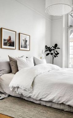 a bedroom with white walls and pictures on the wall above the bed, along with an area rug