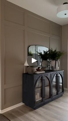 a living room with a large mirror on the wall next to a black console table