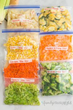 four bags filled with vegetables sitting on top of a counter next to carrots and celery