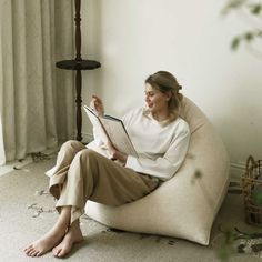 a woman sitting on a bean bag chair reading a book