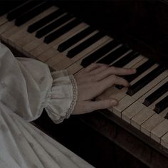 a close up of a person's hand on a piano keys with white dress