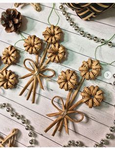 several wooden ornaments are arranged on a white wood table with beads and pineconi