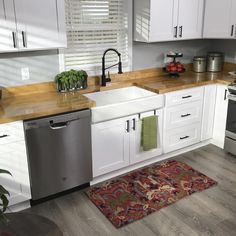 a clean kitchen with white cabinets and stainless steel dishwasher, stove top oven, sink area rug and silver appliances