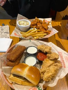 two baskets filled with food sitting on top of a table next to fries and coleslaw