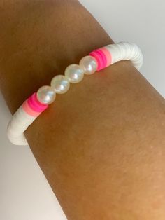 a woman's arm with a pink and white beaded bracelet