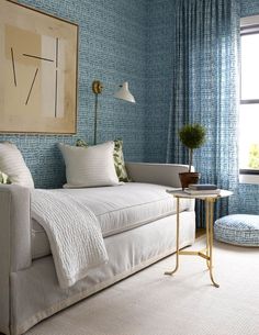 a bedroom with blue wallpaper and white bed in the corner next to a window