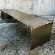 a large metal bench sitting in front of a concrete wall with no one around it