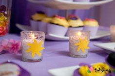 two candles sitting on top of a table next to cupcakes