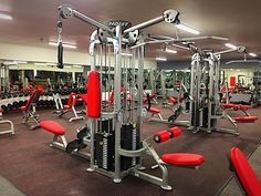 a gym with rows of machines and red seats