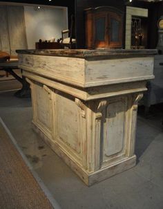 an old wooden sink on top of a wooden table in front of a white house