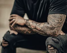 a man with tattoos sitting on a bench