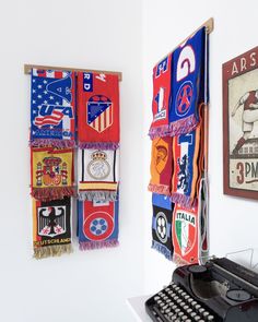 an old typewriter sitting next to a wall with many different flags hanging on it