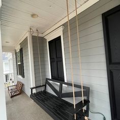 a black porch swing sitting on the side of a house