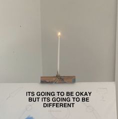 a lit candle sitting on top of a sign with the words it's going to be okay but it's going to be different