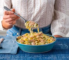 a person holding a spoon full of pasta with tuna