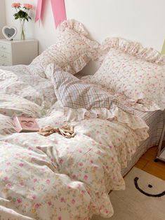 an unmade bed with pink and white flowers on it