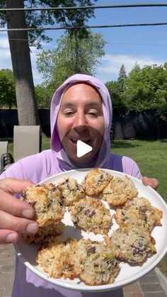 a woman holding a plate with cookies on it in front of her face and smiling at the camera