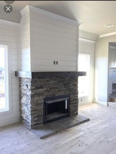 an empty living room with a fireplace in the center and windows on both sides,