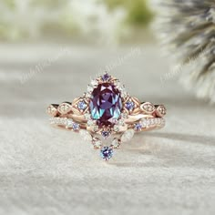 a ring with an oval shaped purple stone surrounded by smaller blue and white diamonds on top