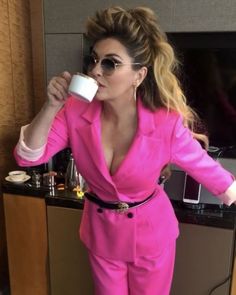 a woman in a pink suit drinking from a cup