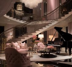 a living room filled with furniture and a grand piano in front of a stair case