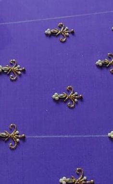 many small gold florets are on a purple tablecloth with white beads and pearls