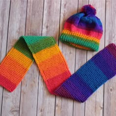 two knitted hats and mittens sitting on top of a wooden floor next to each other