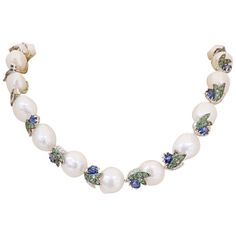 This beautiful 18 karat white gold collar necklace is designed with 22 semi Baroque Pearls , approximately 12mm. each. The pearls are connected by 18 kt white gold leaf sections with Diamonds and Tsavorites and a round Blue Sapphire. The total length of the necklace is 19.5 ". There is a 2" section that is detachable allowing you to wear the necklace at choker length. Total Diamond Weight 44=0.51 carats Total Blue Sapphire Weight 22= 12.16 carats Total Tsavorites 154= 5.11 carats Stamped 750 18 Luxury Pearl Necklace With Colorful Round Beads, Luxury Blue Baroque Pearl Necklaces, Luxury Blue Baroque Pearl Necklace, Luxury Blue Pearl Chain Jewelry, Luxury Blue Pearl Necklaces, Panconesi Necklace, Pearl Necklace With Sapphire, 1stdibs Jewelry, Pearl Necklace With Diamond