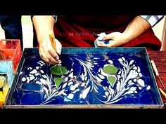 a man is working on an art project with blue and green tiles in front of him