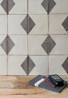 a notebook and pen sitting on top of a wooden table next to a tiled wall