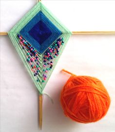 an orange ball of yarn next to a crochet hook with beads and needles