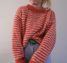 a woman in an orange and white striped sweater is standing with her hands on her hips