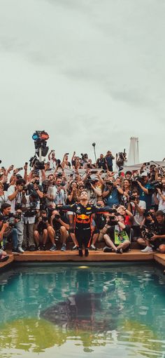 a large group of people sitting on the edge of a pool with cameras around them