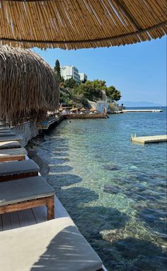 the beach is lined with lounge chairs and thatched umbrellas