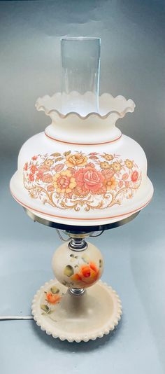 an ornate white and gold dish on a stand with a glass vase in the center