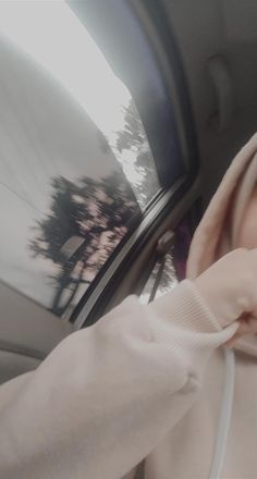 a woman in a car with her head out the window, wearing a white hoodie