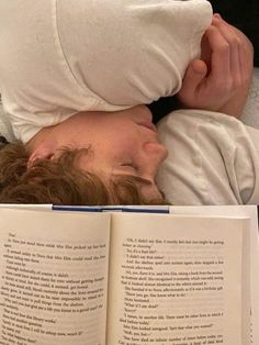 a man laying in bed next to an open book with his head on the pillow