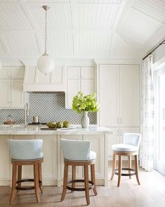 two stools are in front of the kitchen island with white cabinets and counter tops