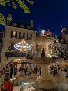 people are gathered around the fountain at night