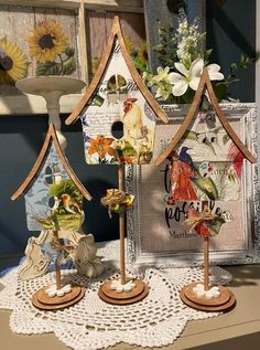 three wooden birdhouses with flowers in them sitting on a table next to a window