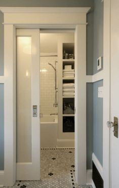 an open door leading to a bathroom with black and white floor tiles on the walls